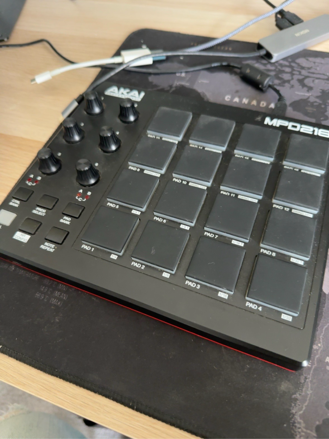 Akai MPD218 controller with sixteen drum pads and eight knobs on the studio desk.